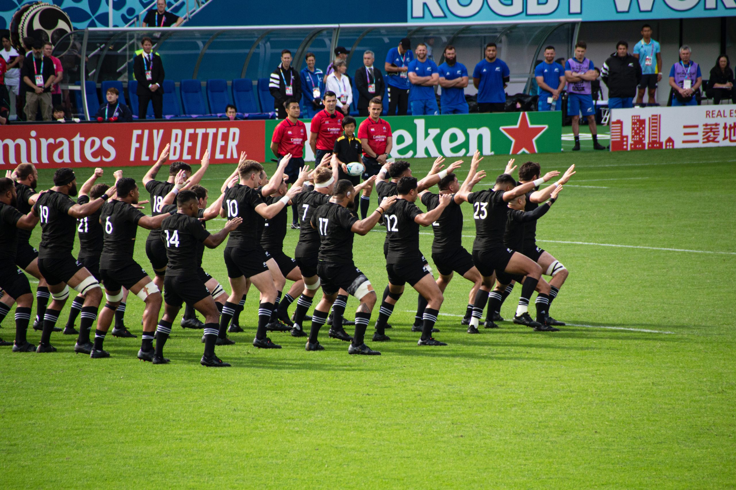 The New Zealand All Blacks performing the Haka with rugby match officials watching on